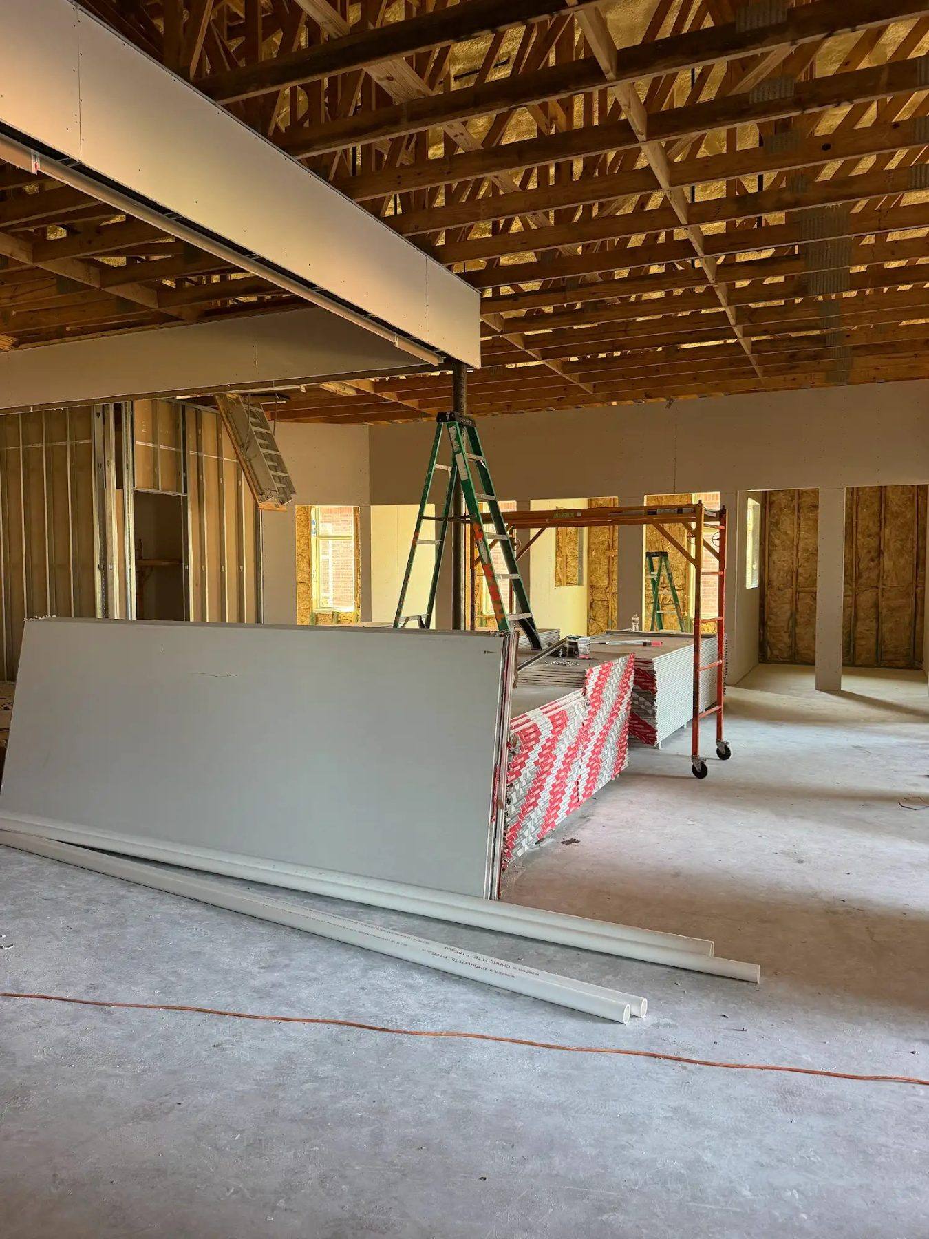 Office walls being drywalled under open trusses at the Aleaf Insurance build-out in Frisco, TX