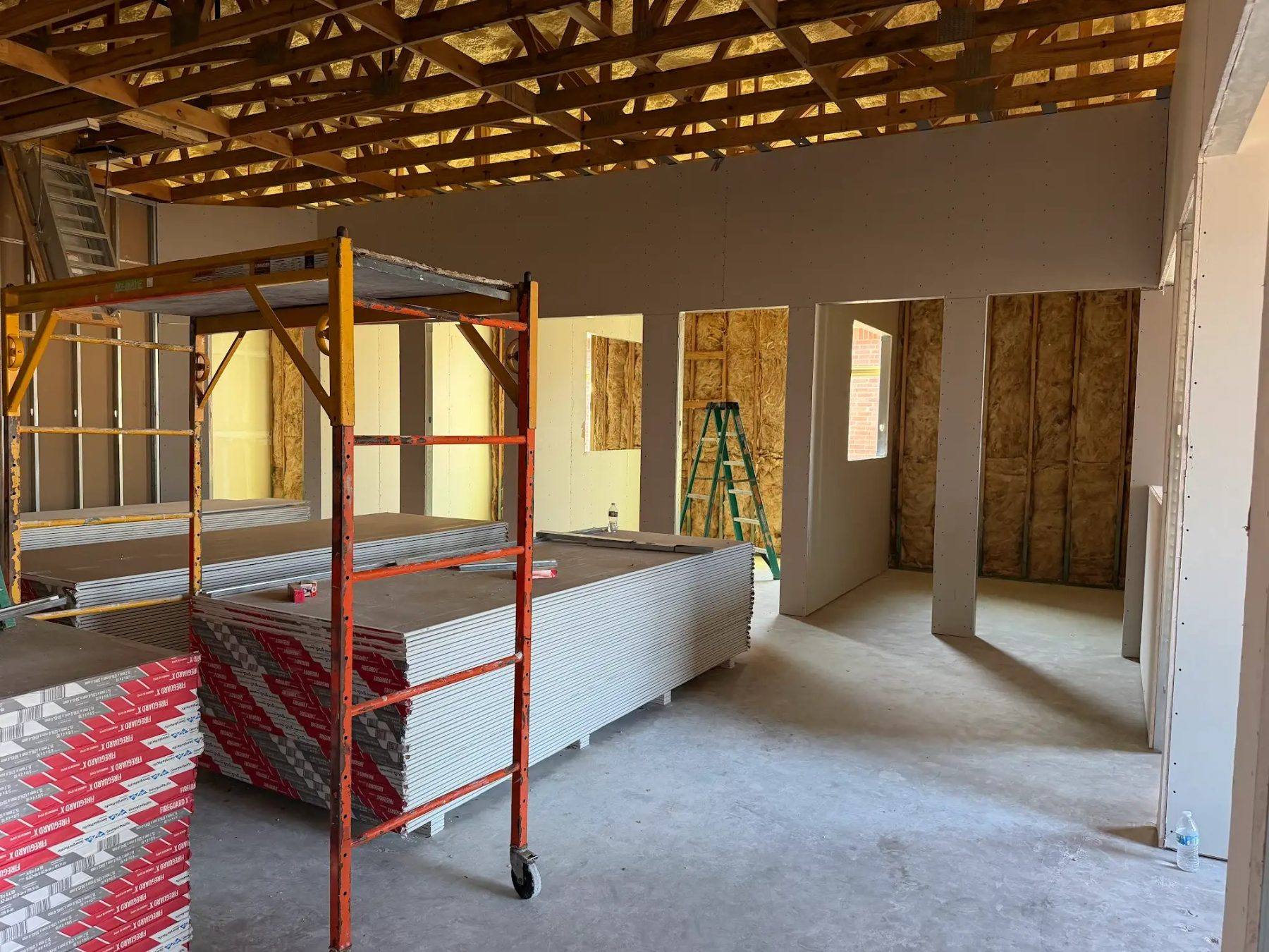 Private offices framed and insulated with drywall staged on scaffolding at the Aleaf Insurance build-out in Frisco, TX