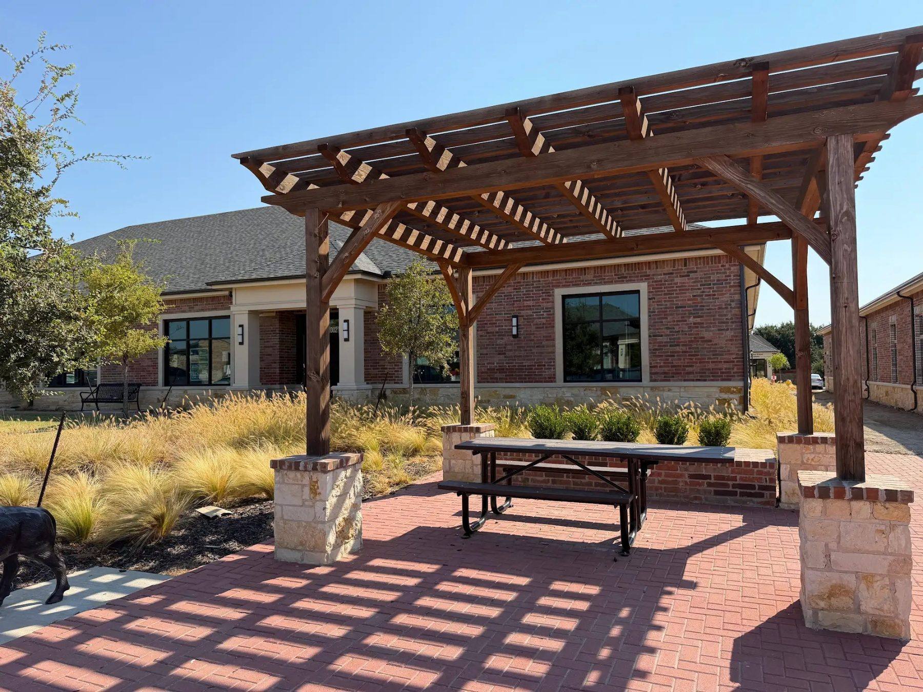 Covered pergola and picnic table outside the Aleaf Insurance office building in Frisco, TX