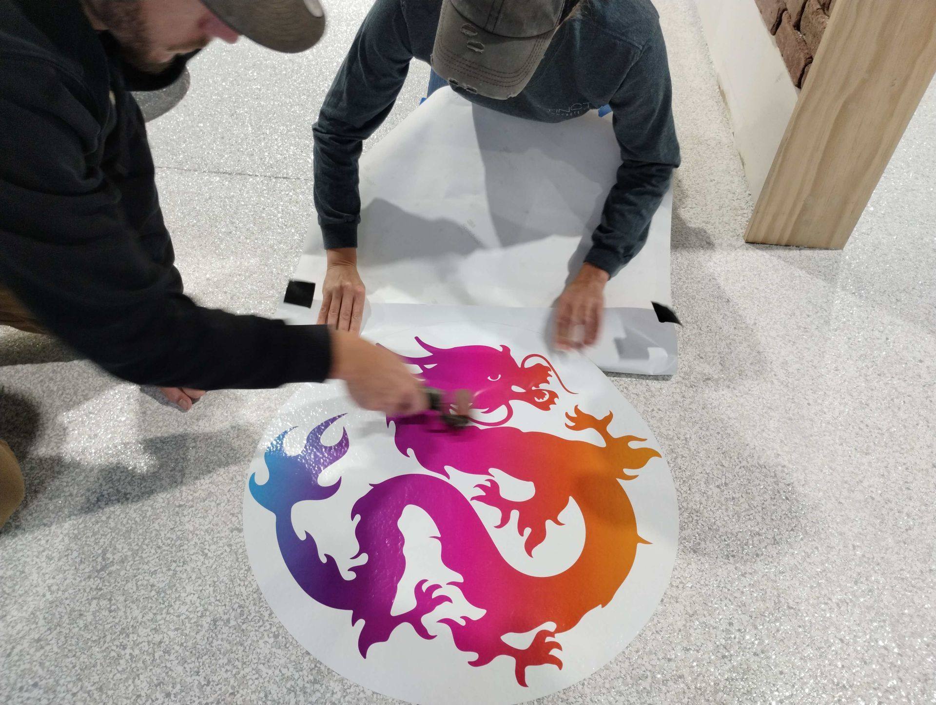 Installers trimming the academy’s dragon logo before setting it into the new epoxy floor at Kung Fu Academy of North Texas in McKinney, TX