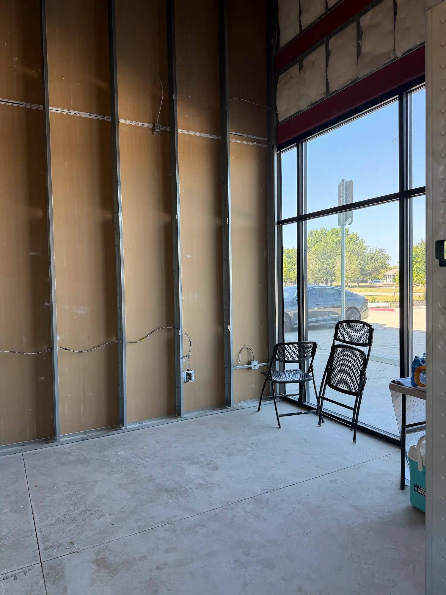 Future office of Calibrate Pilates Studio in McKinney, TX, framed against the storefront glass before drywall