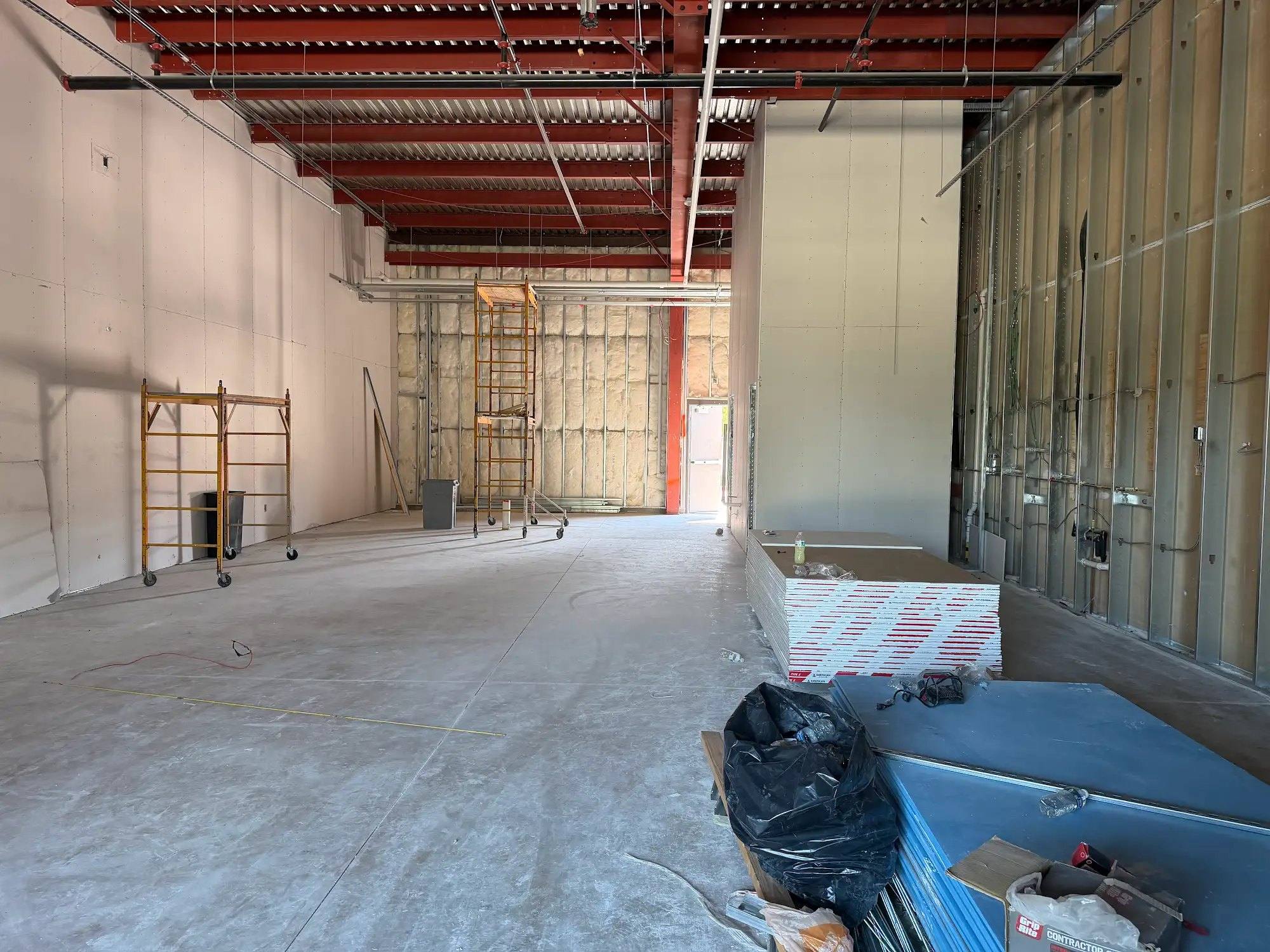 Future workout area of Calibrate Pilates Studio in McKinney, TX as an open shell with a concrete slab and exposed roof deck
