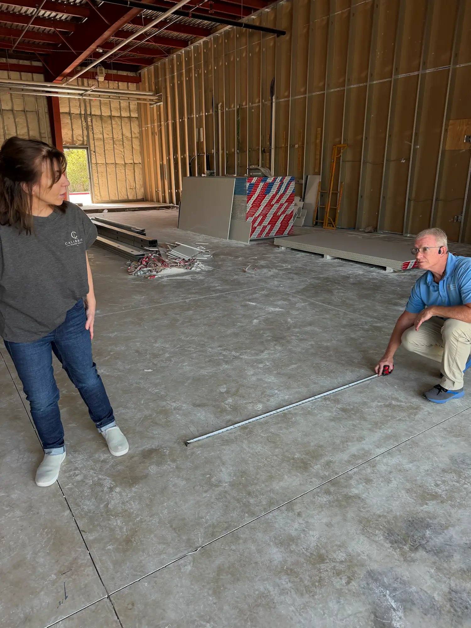 Measuring out interior wall placement on the slab at Calibrate Pilates Studio in McKinney, TX