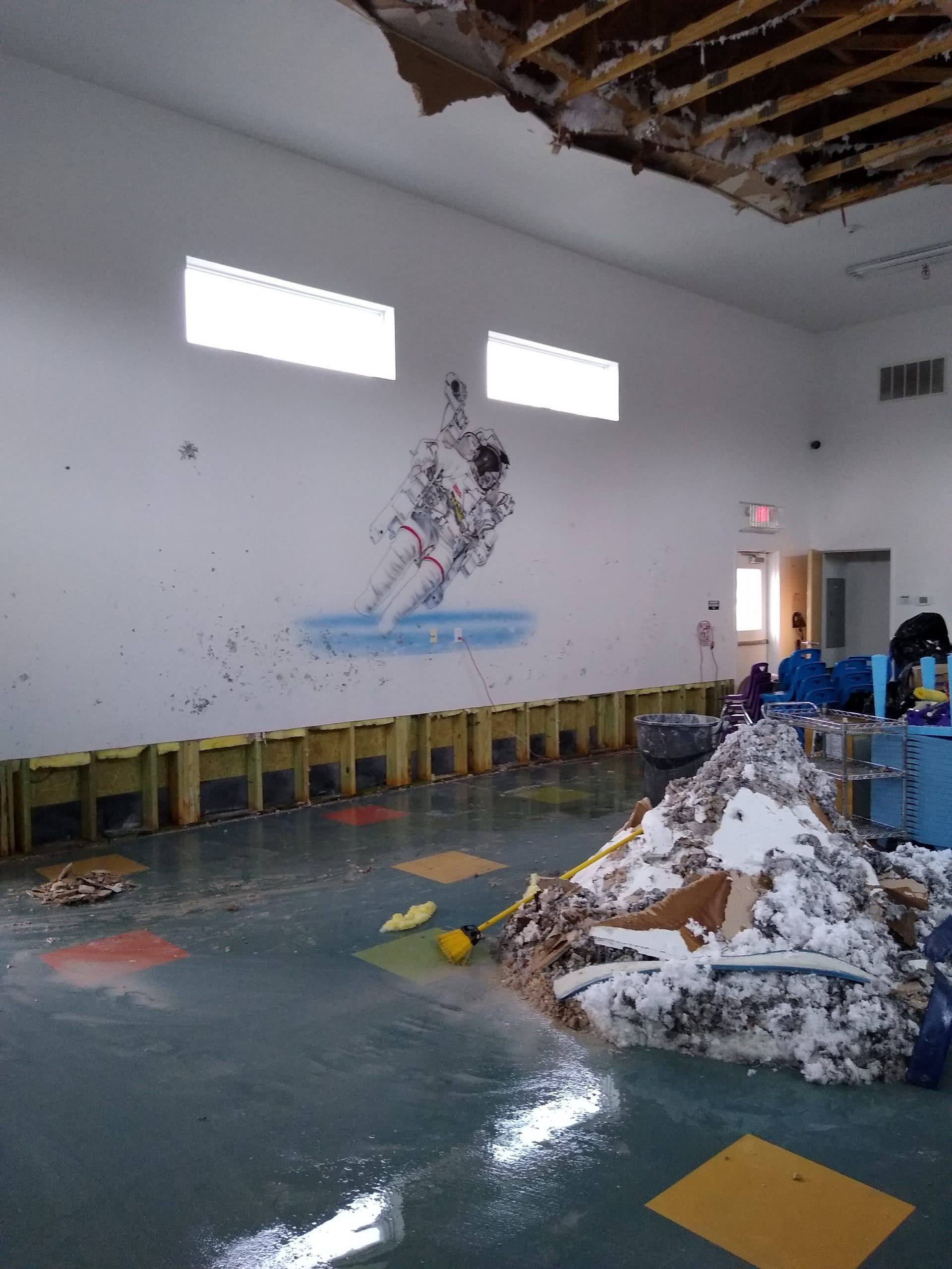 The flooded gymnasium in February 2021, with collapsed ceiling material and soaked insulation piled on the floor after two pipes burst during the Texas freeze
