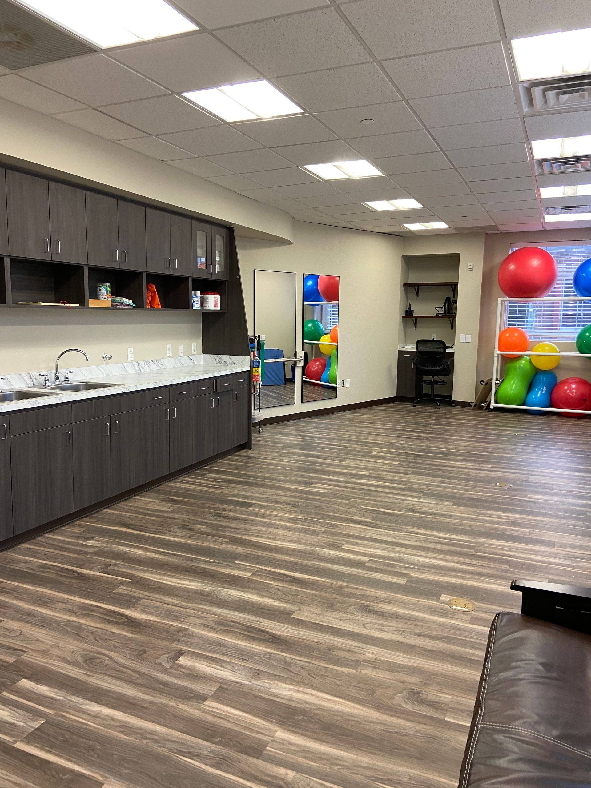 After: the same treatment room at Building Bridges Through Communication in Frisco, TX, finished with new plank flooring and set up with therapy balls and mirrors