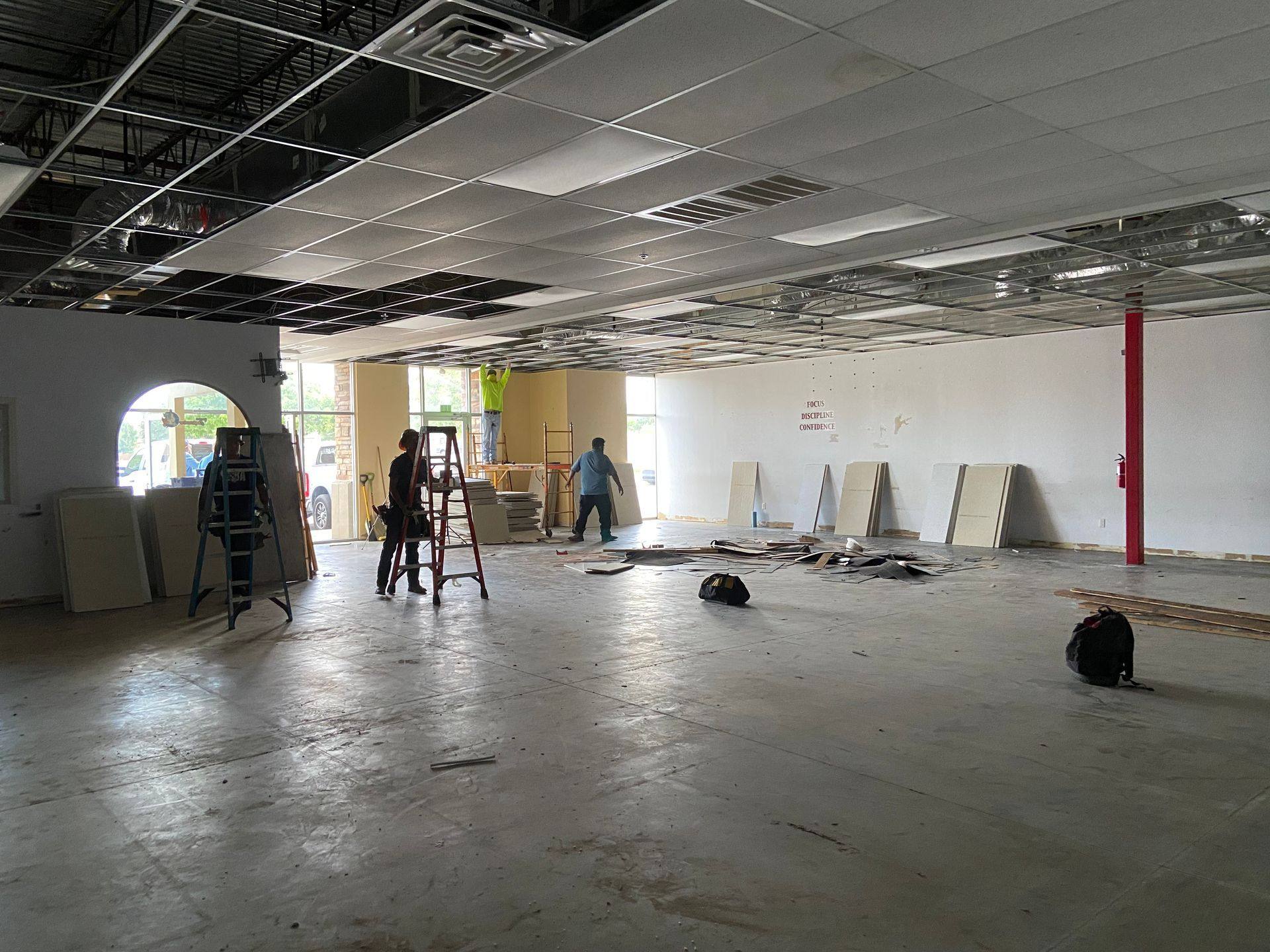 Demolition: the main floor of the former martial arts studio in Denton, TX, its “Focus Discipline Confidence” wall lettering still up as the ceiling comes down