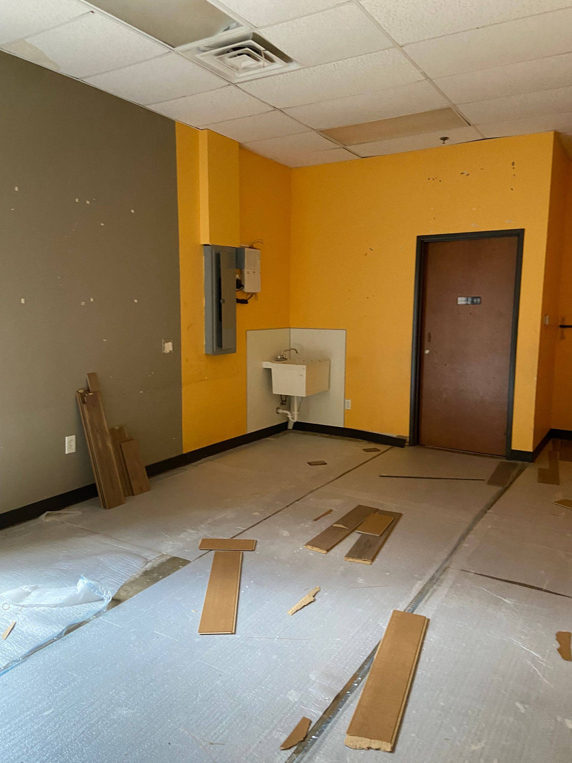Before: a back room of the former martial arts studio in Denton, TX, with the old paint and the flooring coming up