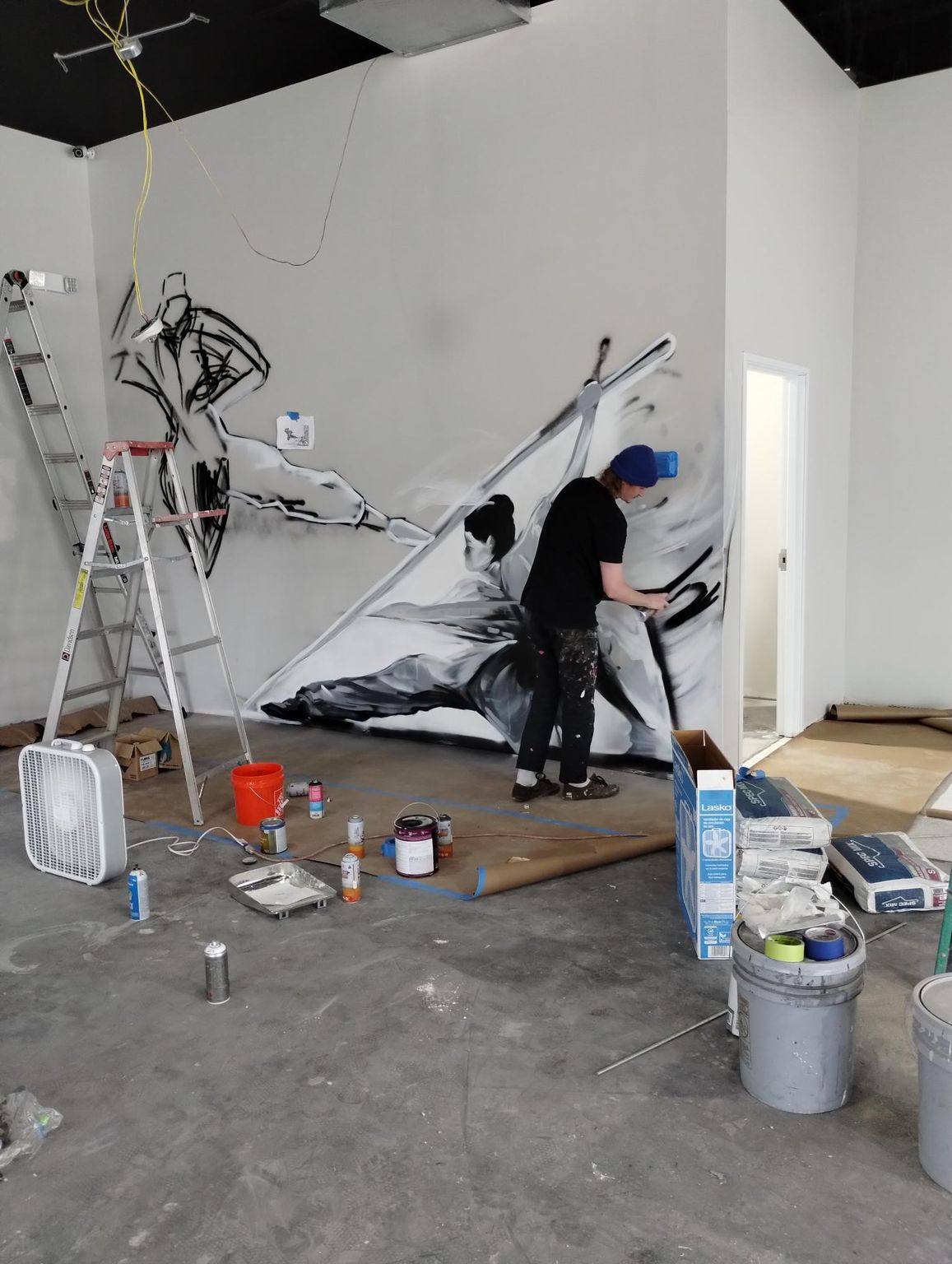 An artist painting the black and white kung fu mural on the finished wall at Kung Fu Academy of North Texas in McKinney, TX